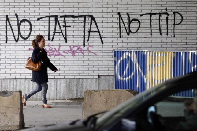 A pedestrian walks past graffiti that reads, "No TAFTA, No TTIP", in Brussels, Belgium, July 27, 2015. REUTERS/Francois Lenoir